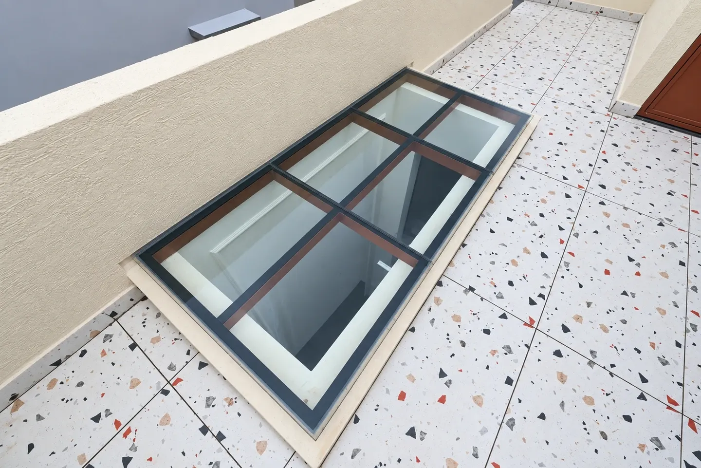 Rectangular glass skylight with a dark metal frame on the rooftop terrace