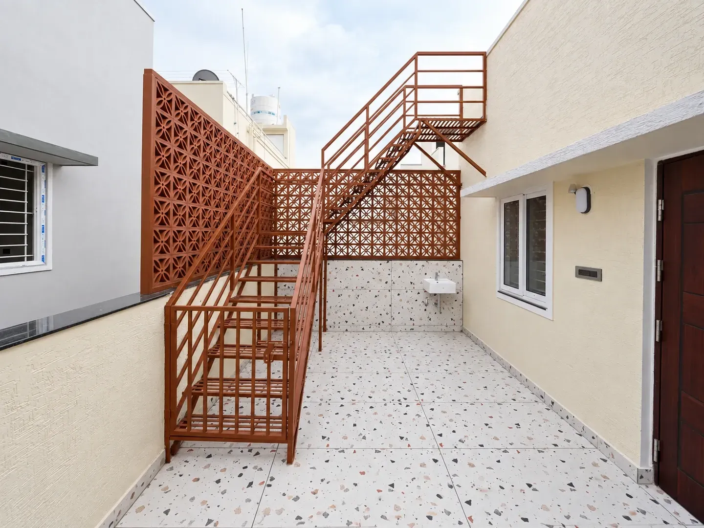 Front view of the exterior metal staircase with jali screening and handrails