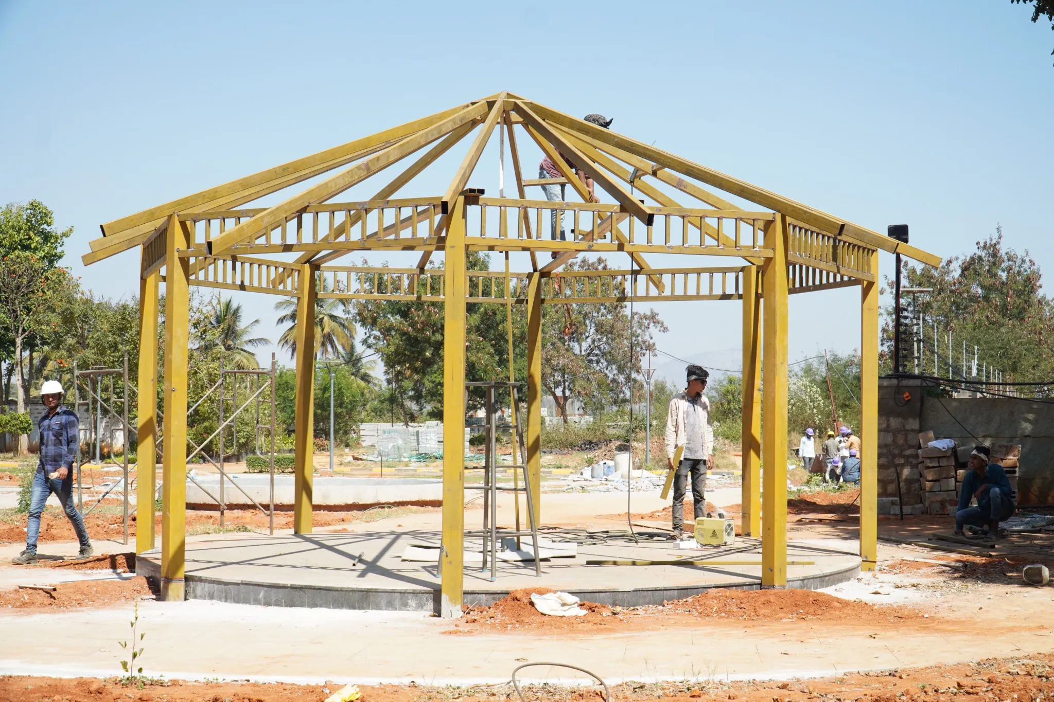 Team assembling a freestanding steel gazebo frame at a project site