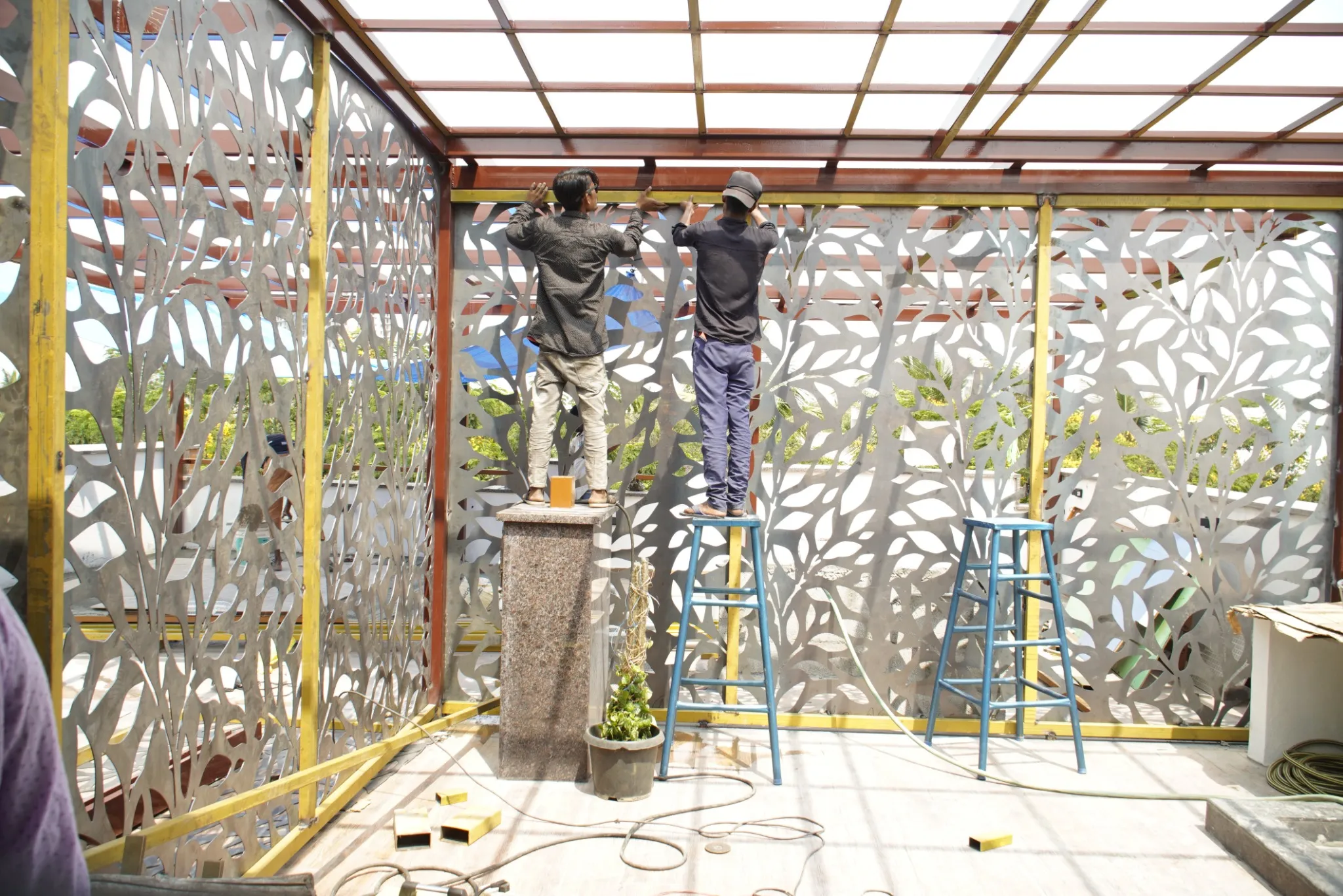 Installation team fitting a pergola framework beside decorative lattice screens