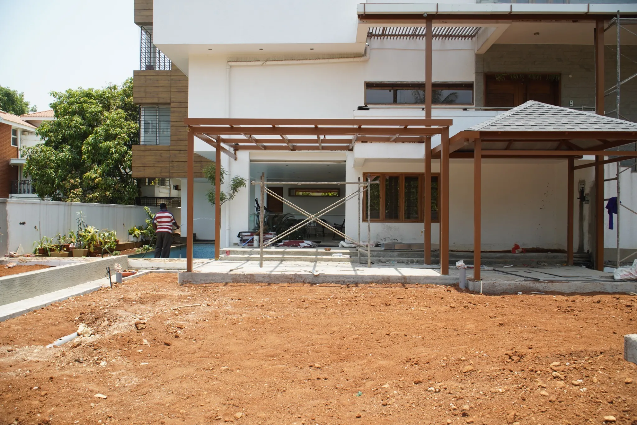 Front view of steel pergola frames and shingle roofing during installation