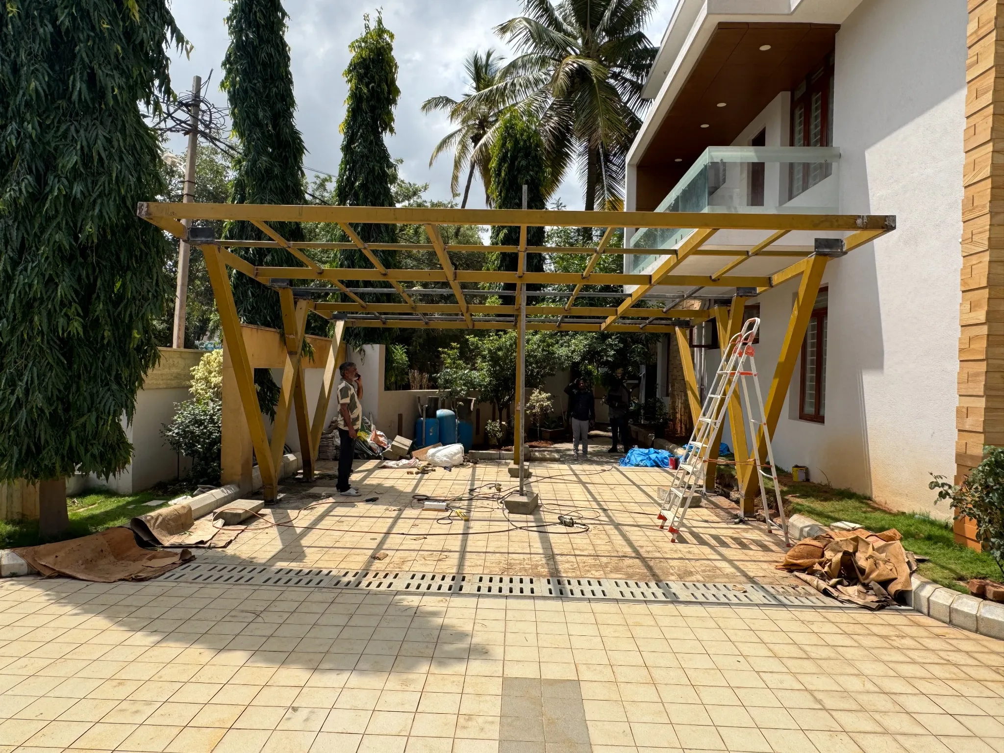 Steel pergola framework being installed beside a home