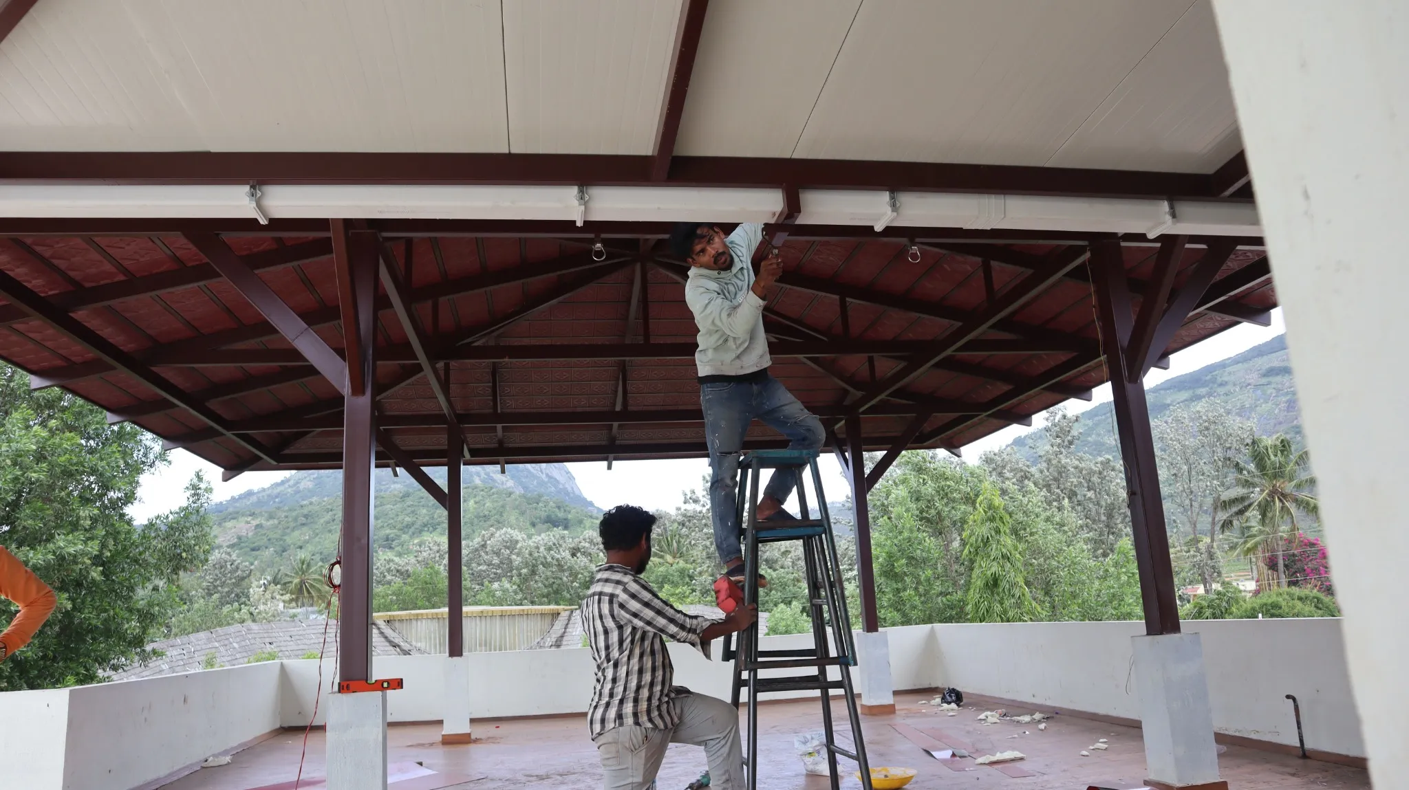 Installation work beneath a Mangalore tile pergola roof