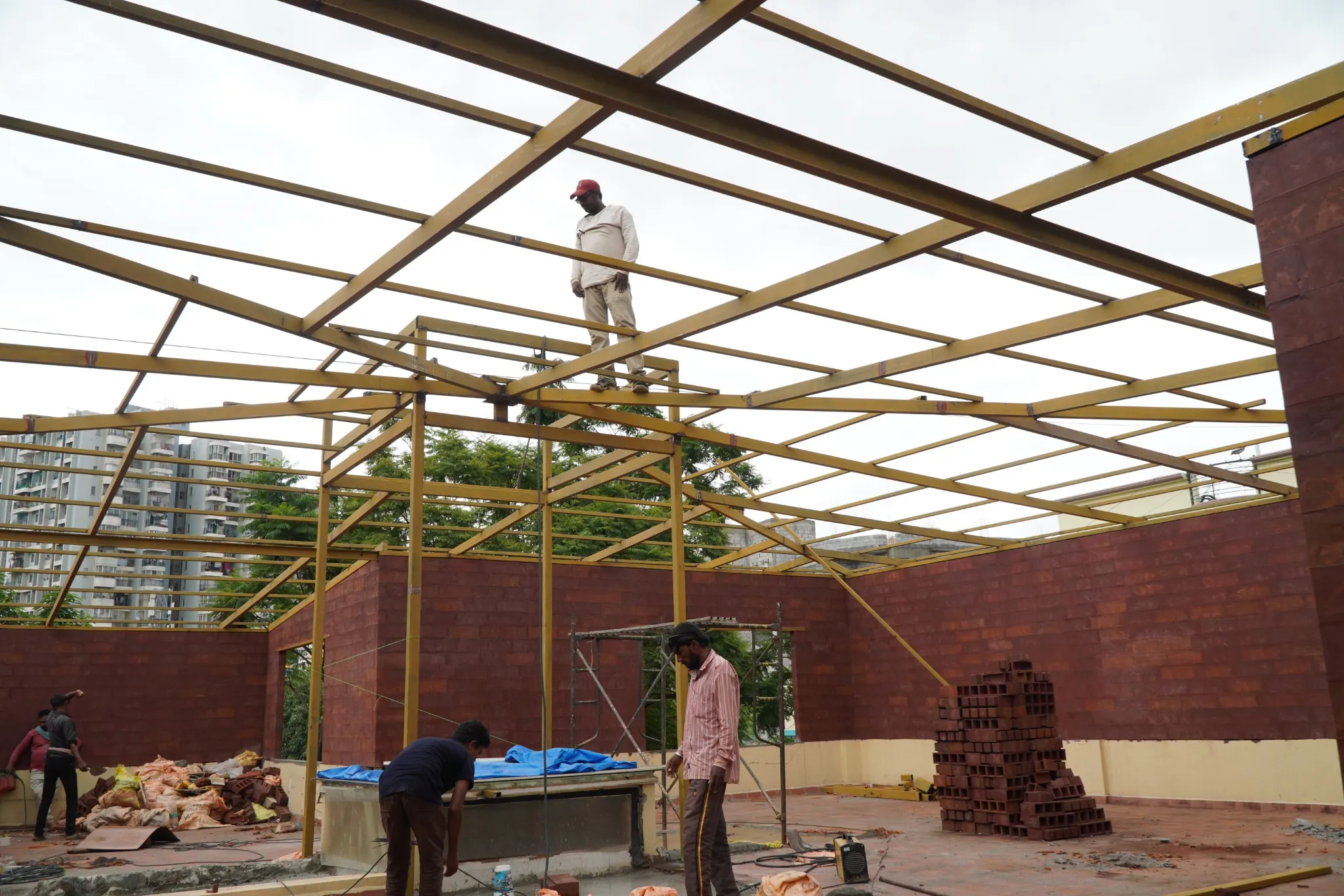 Installation work on a steel framework above a brick courtyard