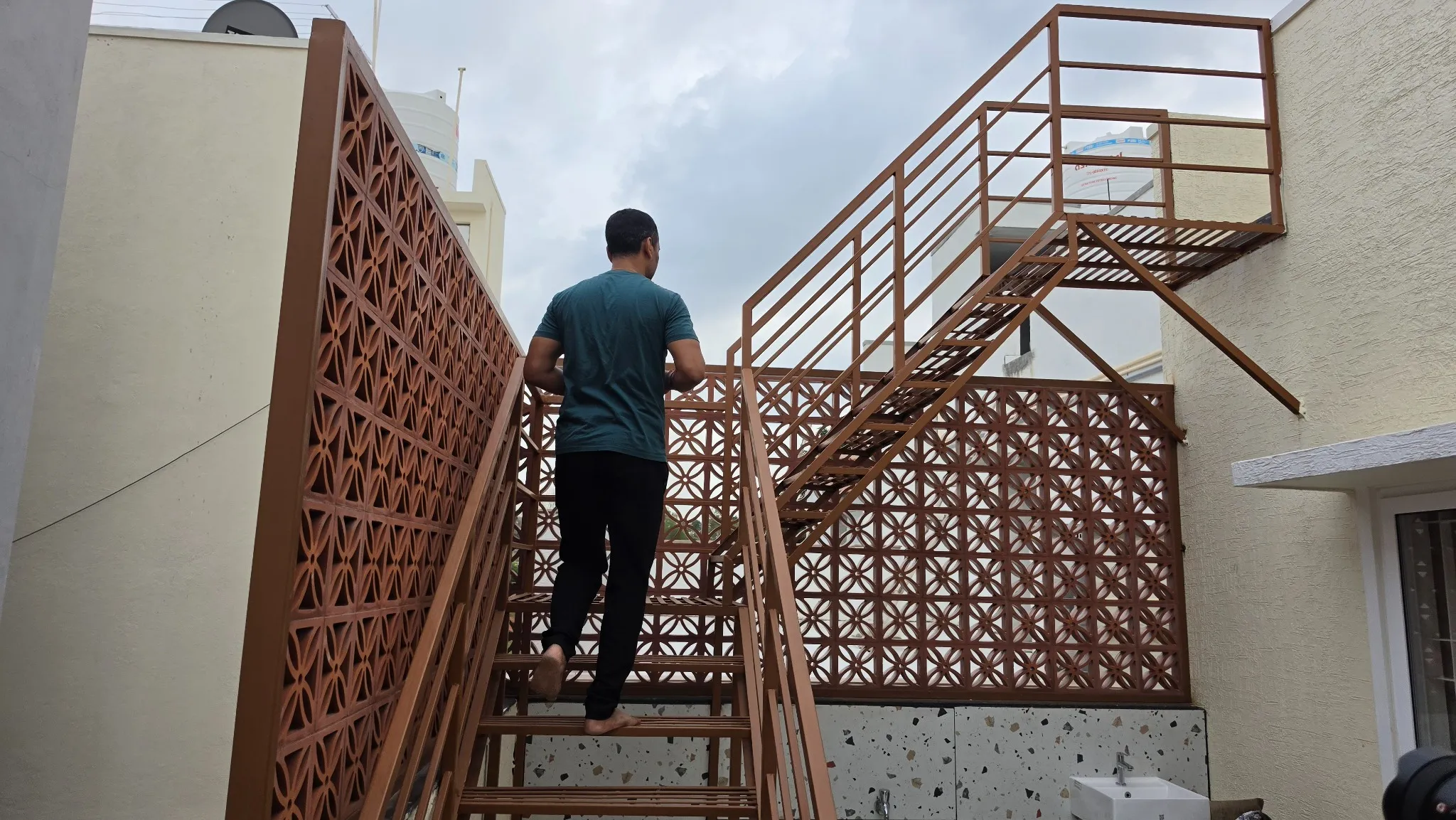 Fabricated metal staircase with railings and terracotta jali screens