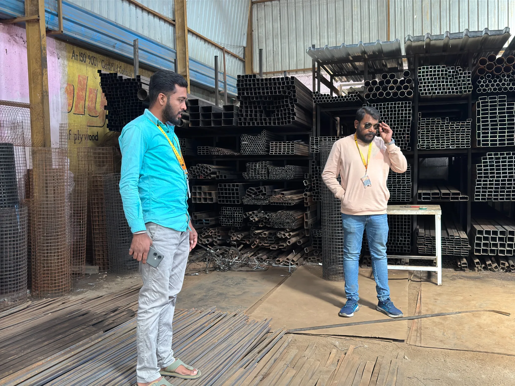 Team members beside stored steel sections in a workshop