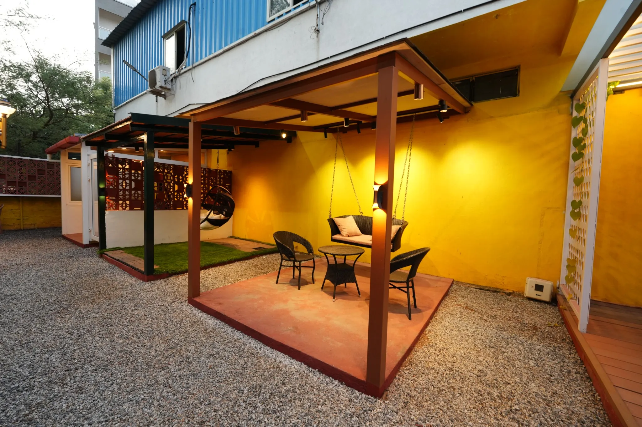 Covered outdoor seating area with warm lighting beside the Experience Centre building