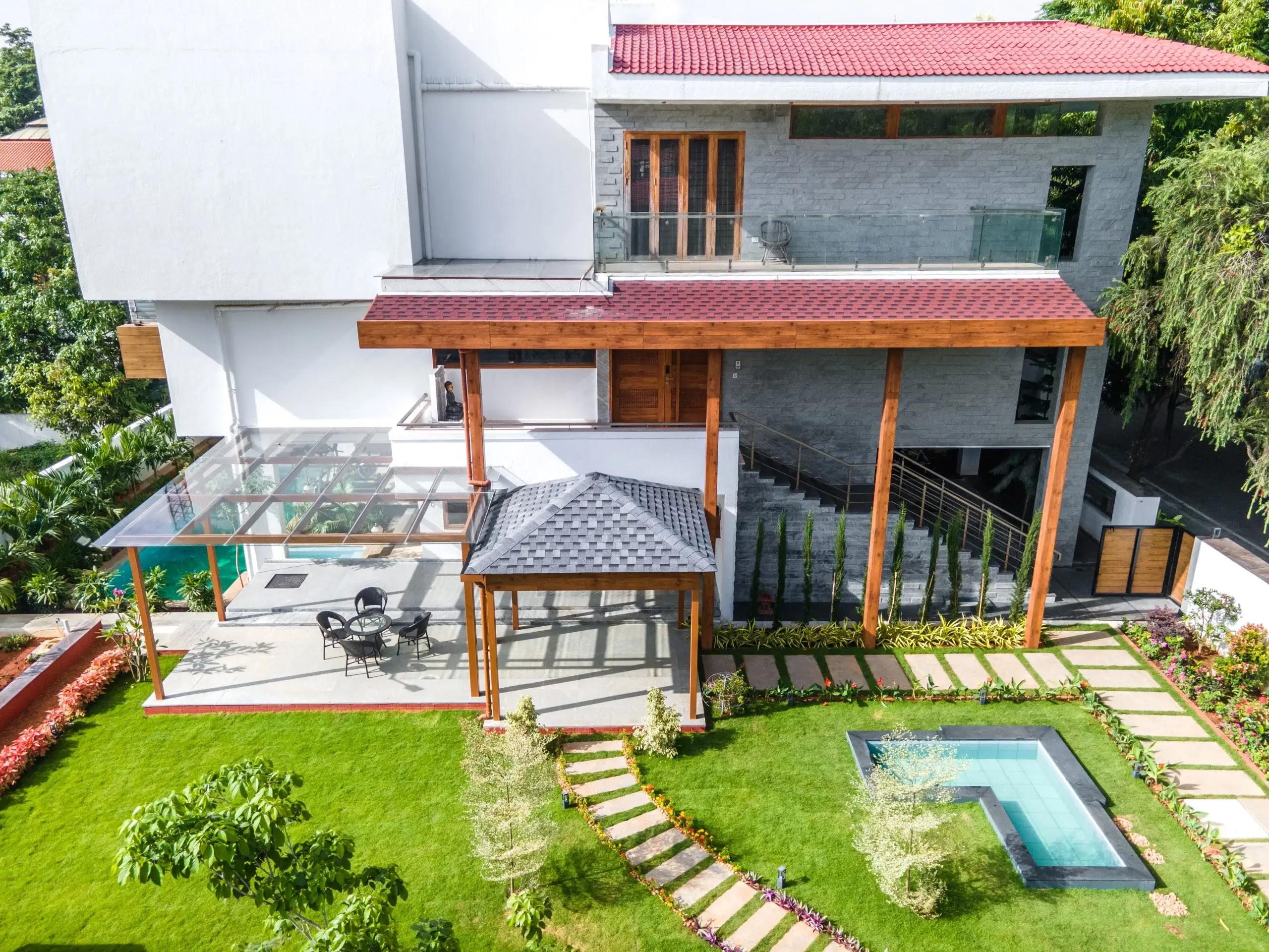 Aerial view of a home featuring a custom wooden pergola, tiled roofing and landscaped garden by PergolaDesign.in