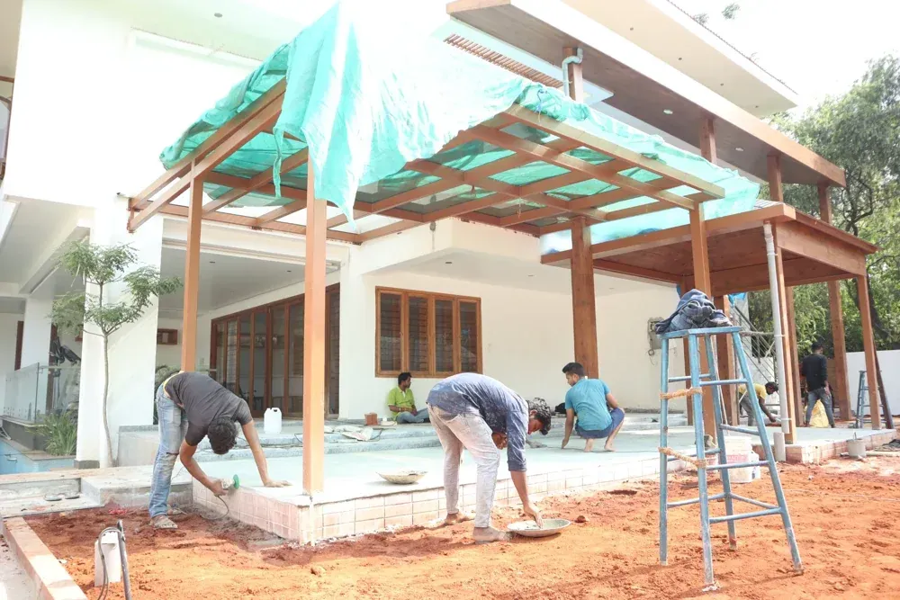 The team works on the patio beneath the pergola before the landscaping is complete.