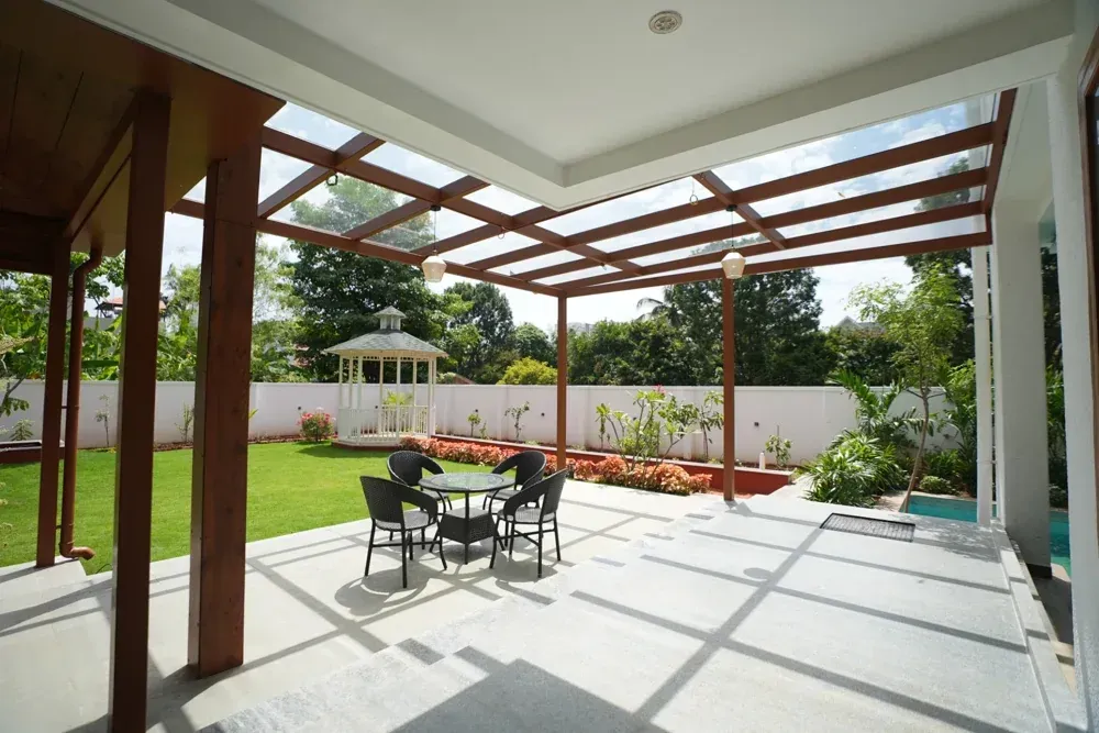 A view from beneath the glass pergola towards the finished lawn and garden gazebo.