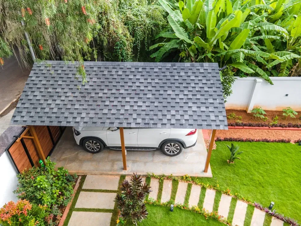 An aerial view of the completed shingles roof, covered car porch and adjoining garden path.