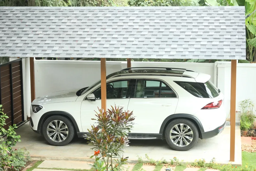 The completed car porch shelters a vehicle beneath the shingles roof.