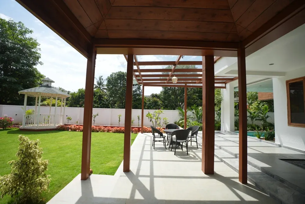 Timber-toned posts connect the covered entrance to the glass pergola and garden.