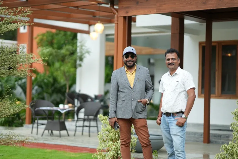 Two visitors pose beside the completed pergola at the project site.