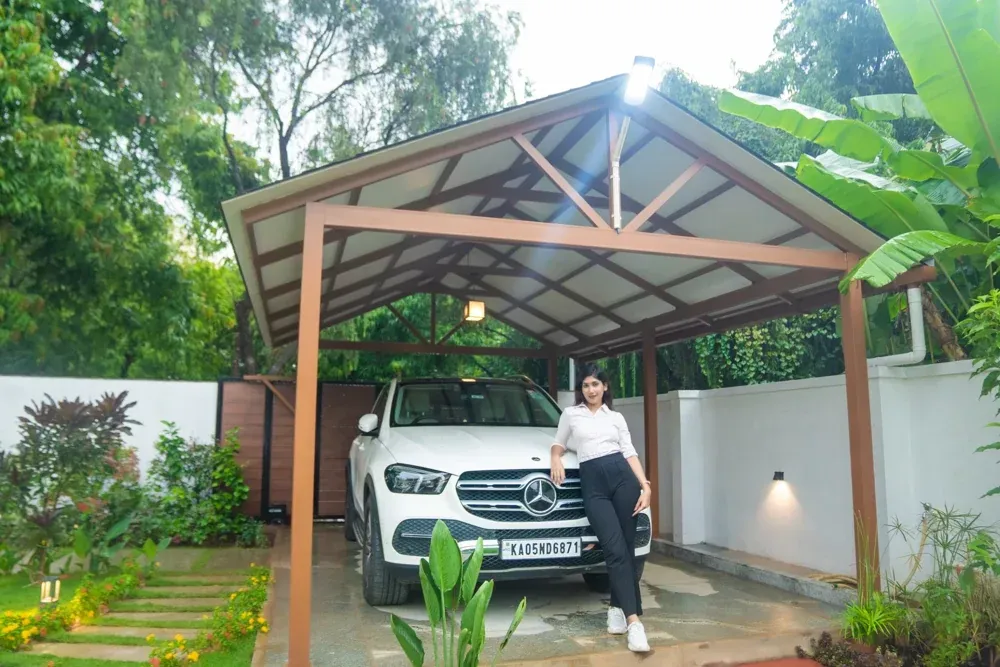 A presenter stands beside a parked vehicle under the completed car porch.