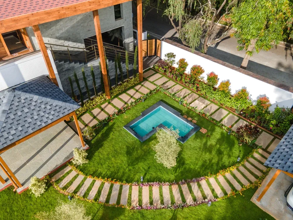 An aerial view follows the curved garden path around the lawn and water feature.