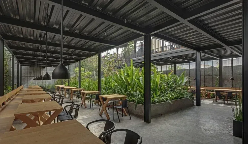 Covered café seating with tables, planters, metal posts and a finished metal roof