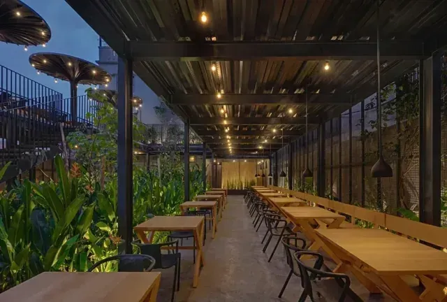 Covered café seating with long tables, pendant lights and planters