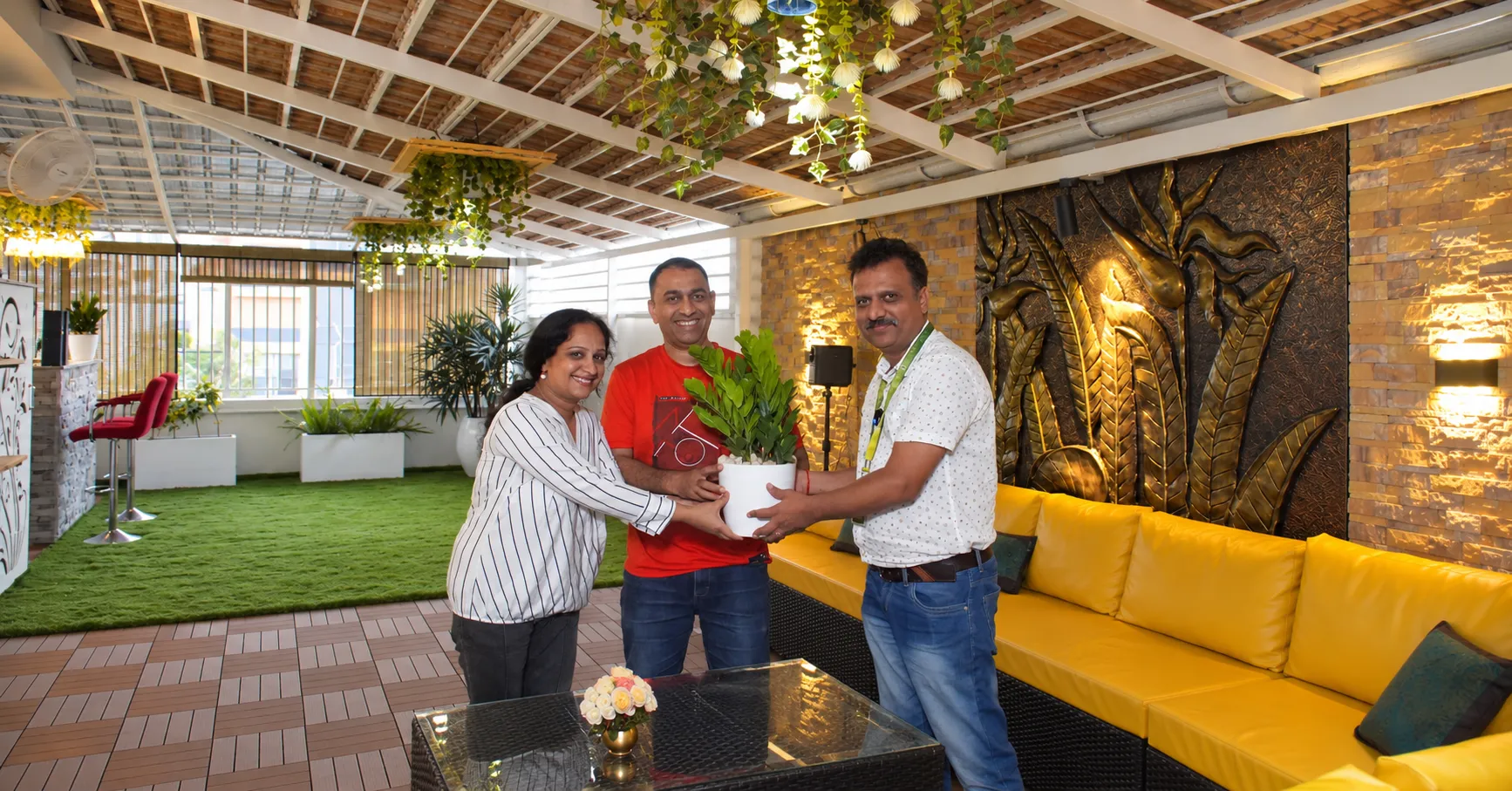 Customers and the Pergola Design.in team sharing a plant at the handover of a completed terrace pergola