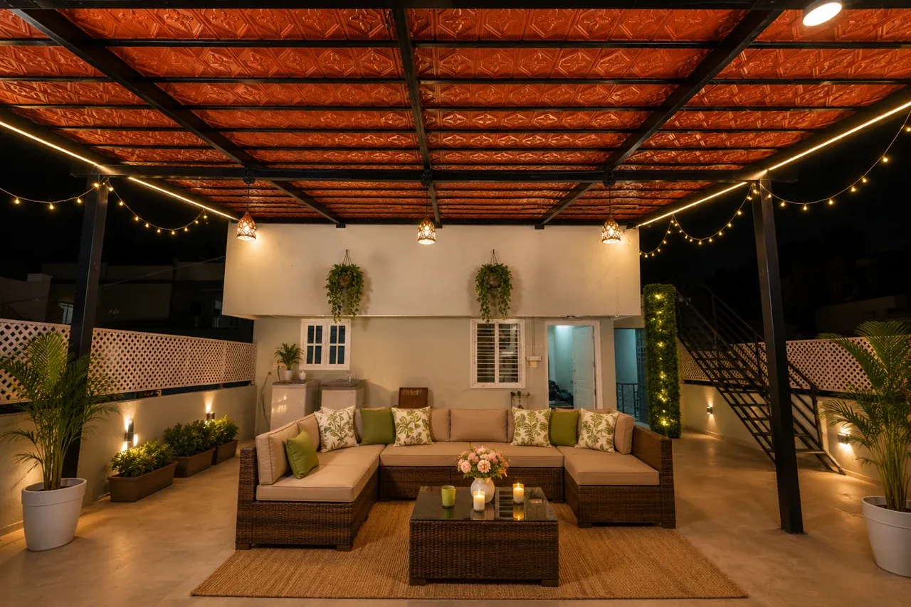 Enhanced terrace view with a Mangalore tile roof, dark metal frame, lounge seating and warm string lights