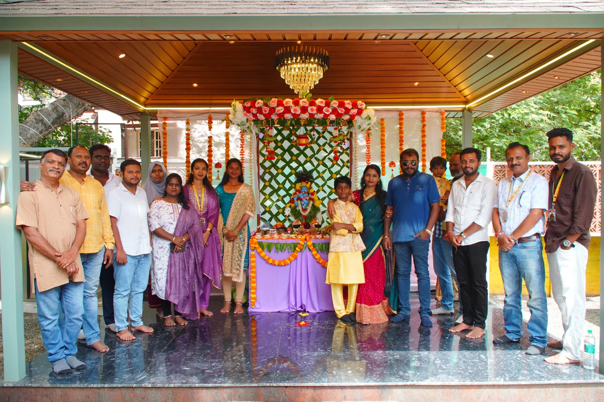 A group gathered beside a flower-decorated festive display beneath a pergola at a Pergola Design.in celebration