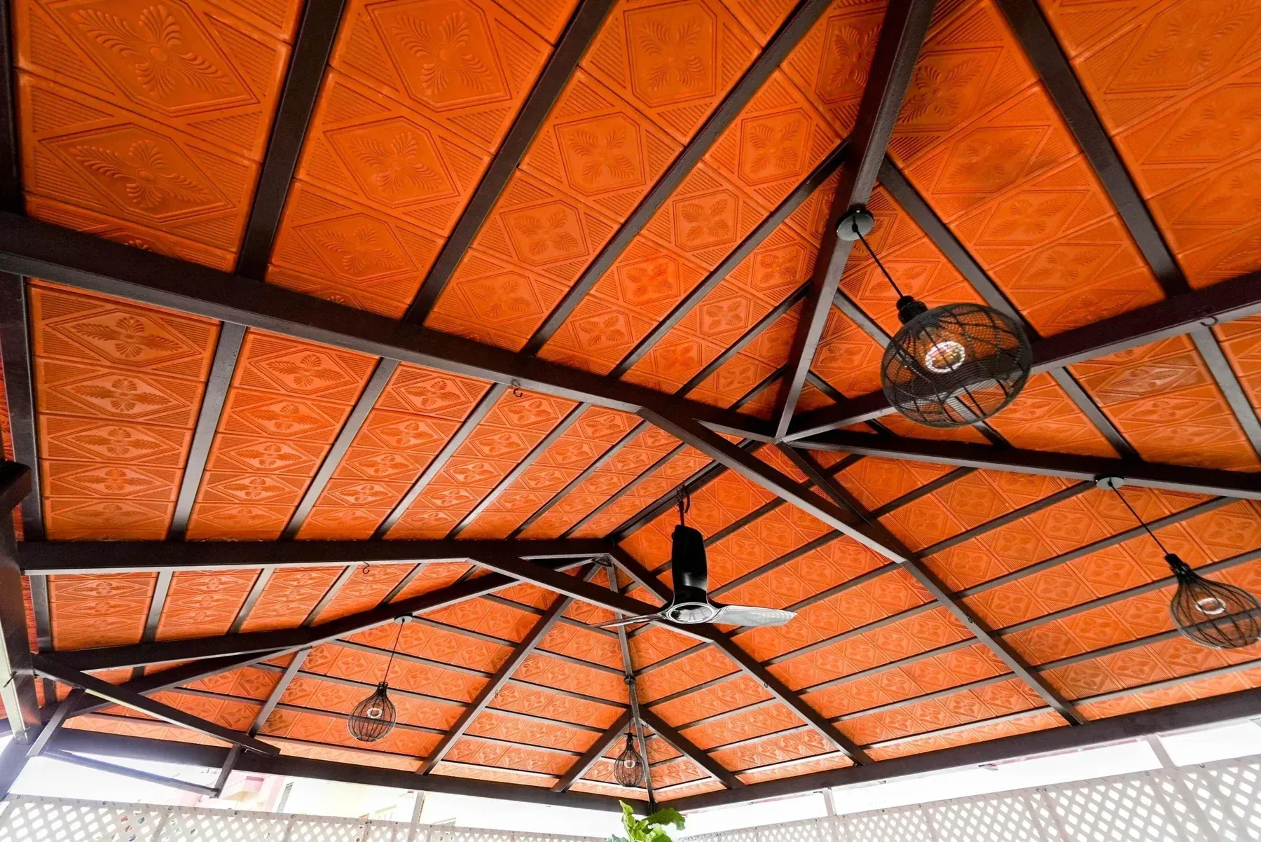 Close view of patterned terracotta roof tiles and dark metal rafters in a Mangalore tile pergola