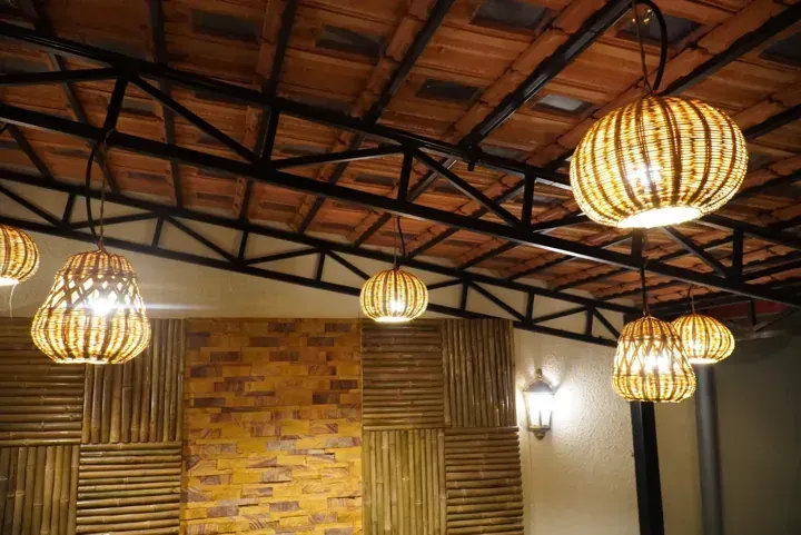 Clay-tile ceiling with dark rafters and woven pendant lights.