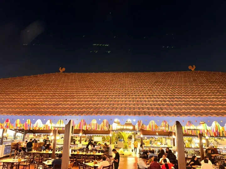 Long clay-tile roof above an outdoor dining area after dark.