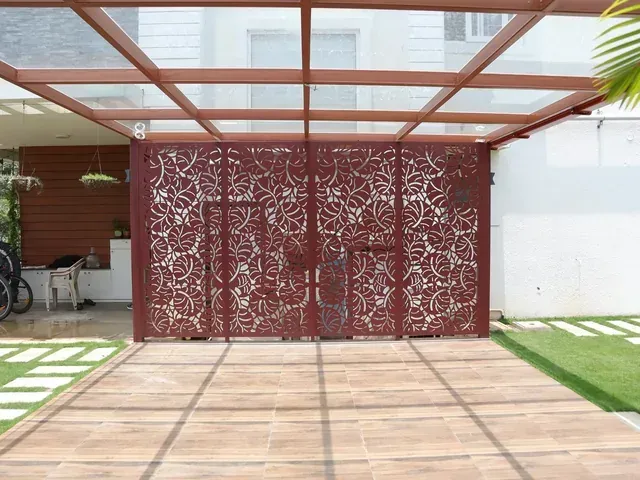 Brown framed glass roof above a terrace with decorative leaf-pattern privacy panels