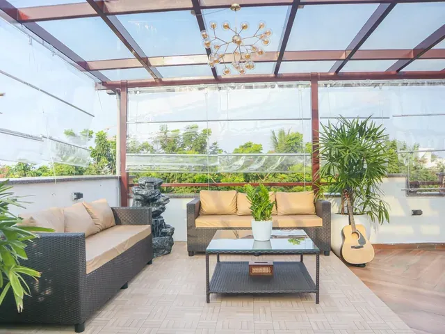 Bright rooftop lounge with a glass roof, sofa seating and planted edges