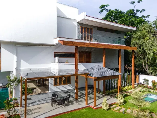 Wide exterior view of a villa with glass pergolas over its outdoor spaces
