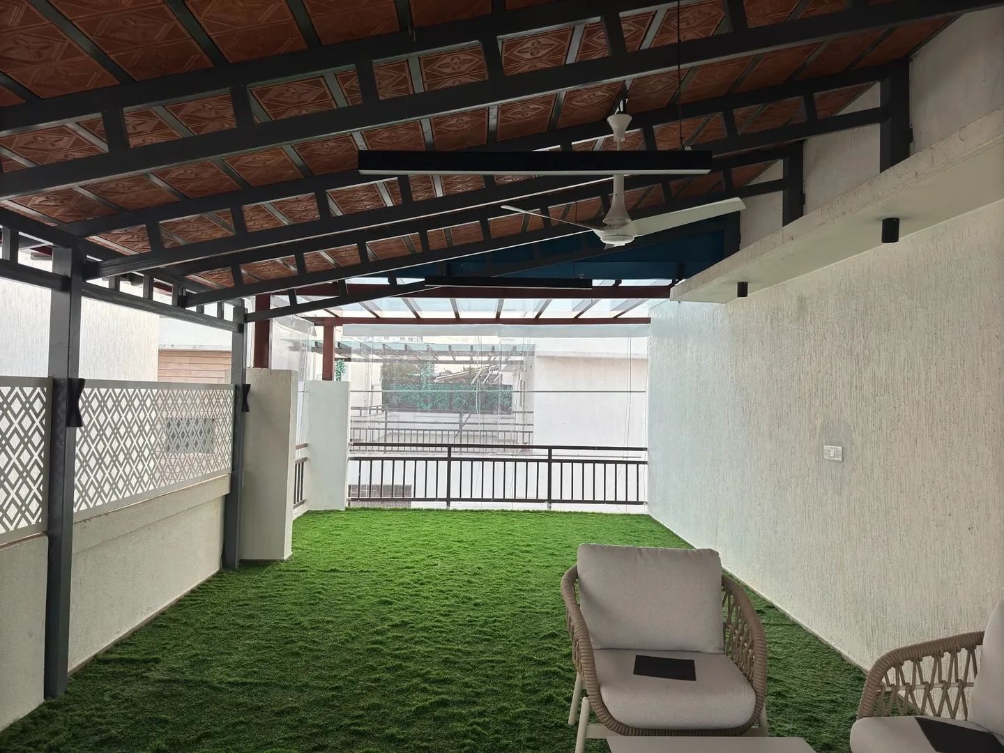 Daylight view along Jancy’s terrace with a tiled roof, dark rafters and green flooring