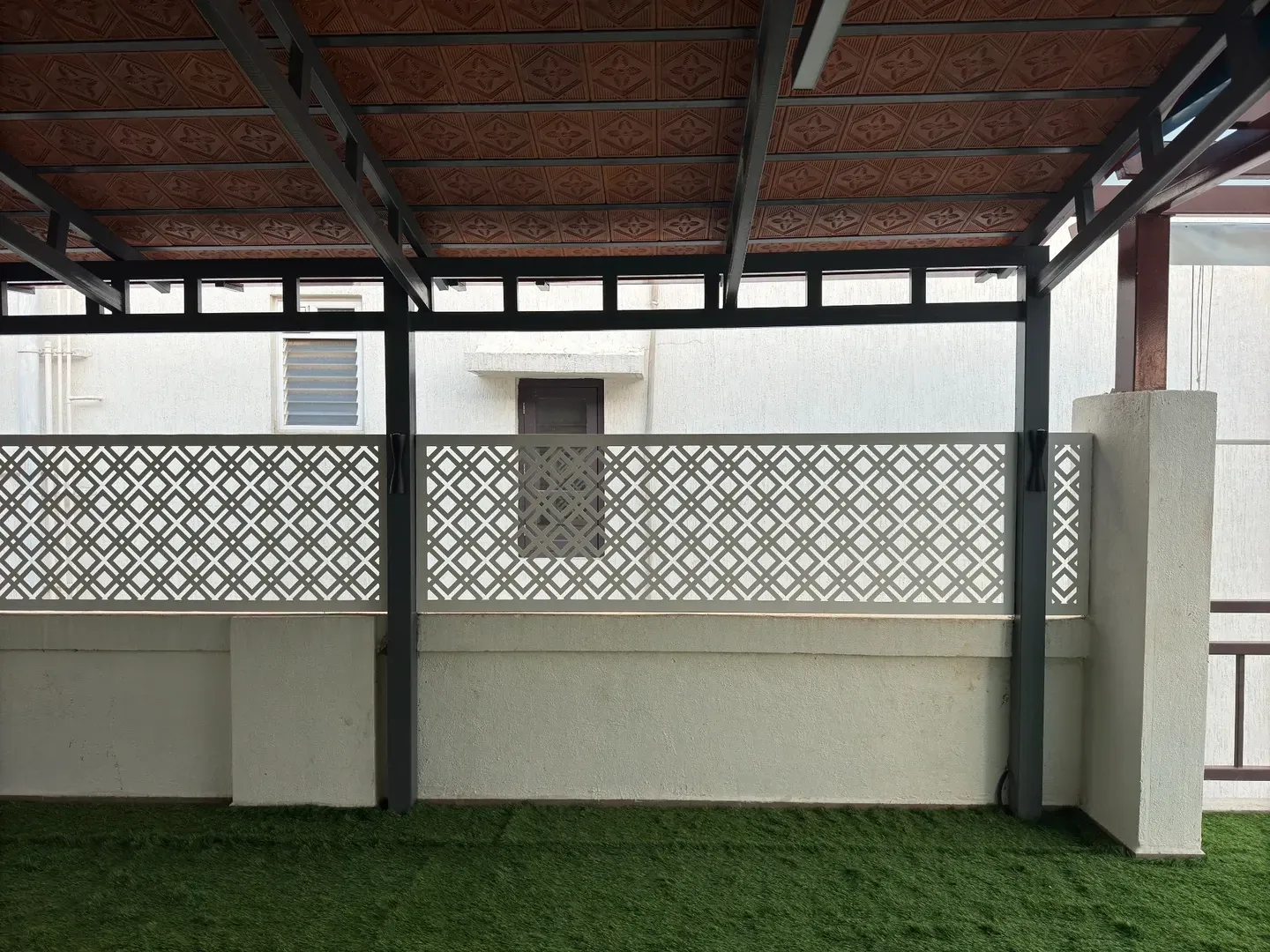 Geometric white CNC panels between dark posts beneath a red tile roof