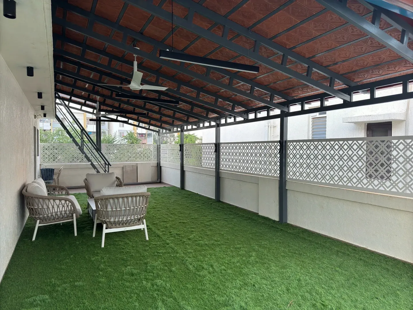 Wide view of the dark pergola frame, patterned fencing and green terrace flooring