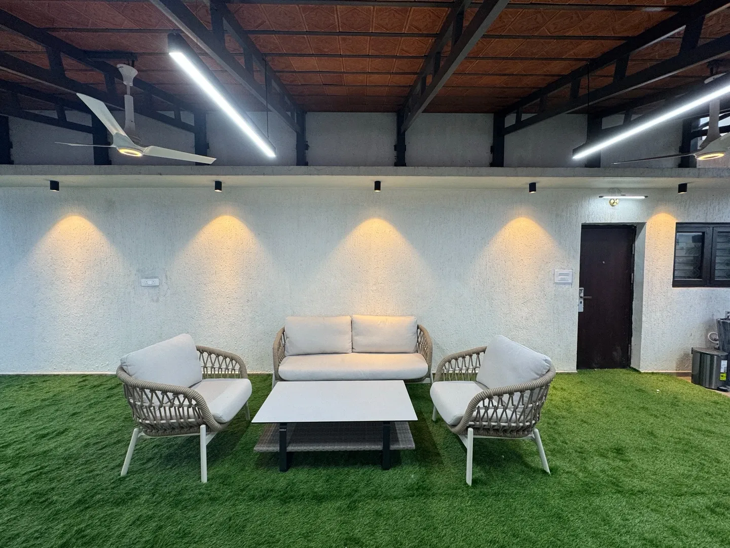 Sofa and chairs beneath the tiled roof with warm wall lights and linear overhead lights