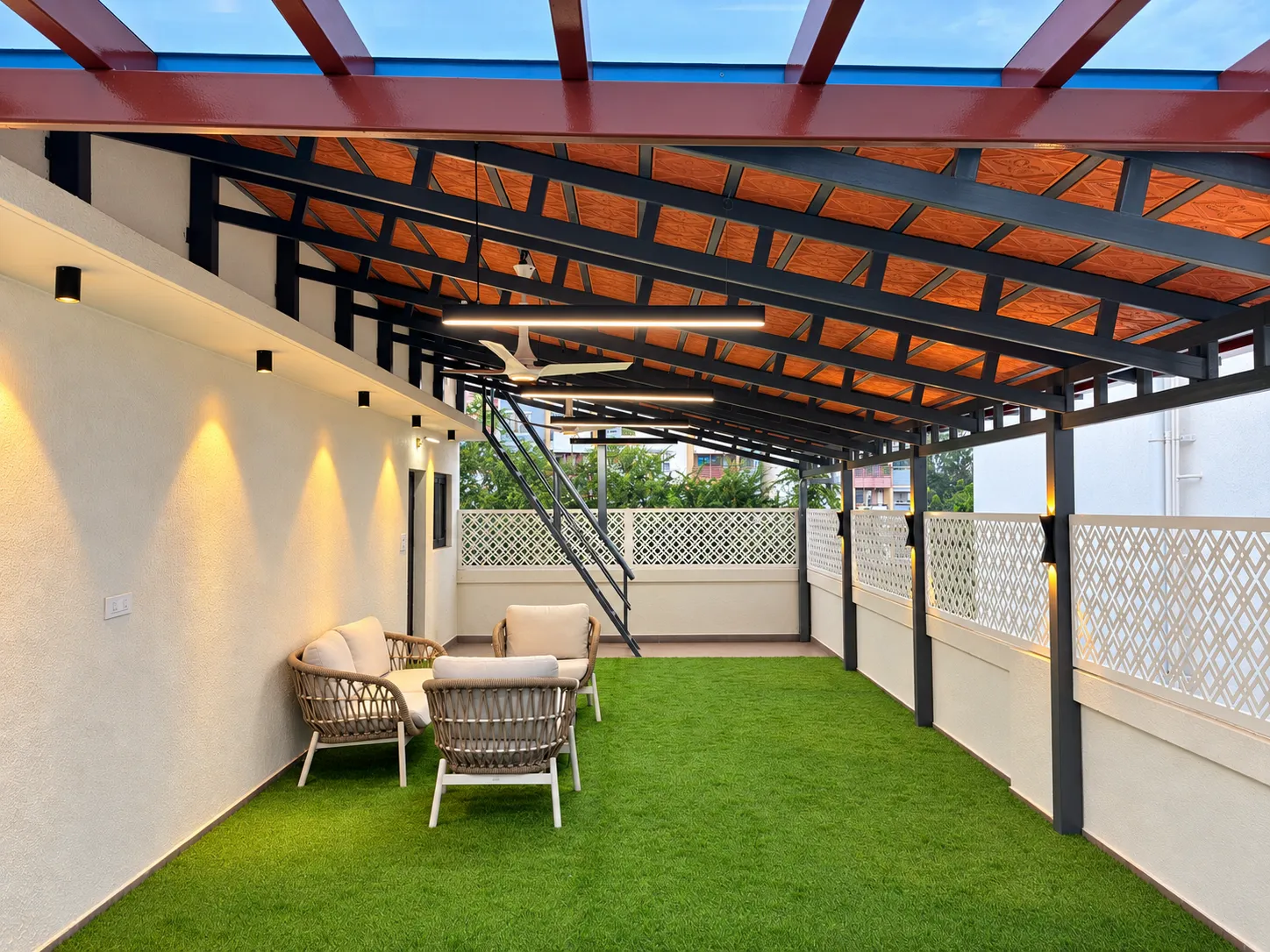 Completed terrace pergola with tiled roofing, exposed steel framing, warm lighting and outdoor seating