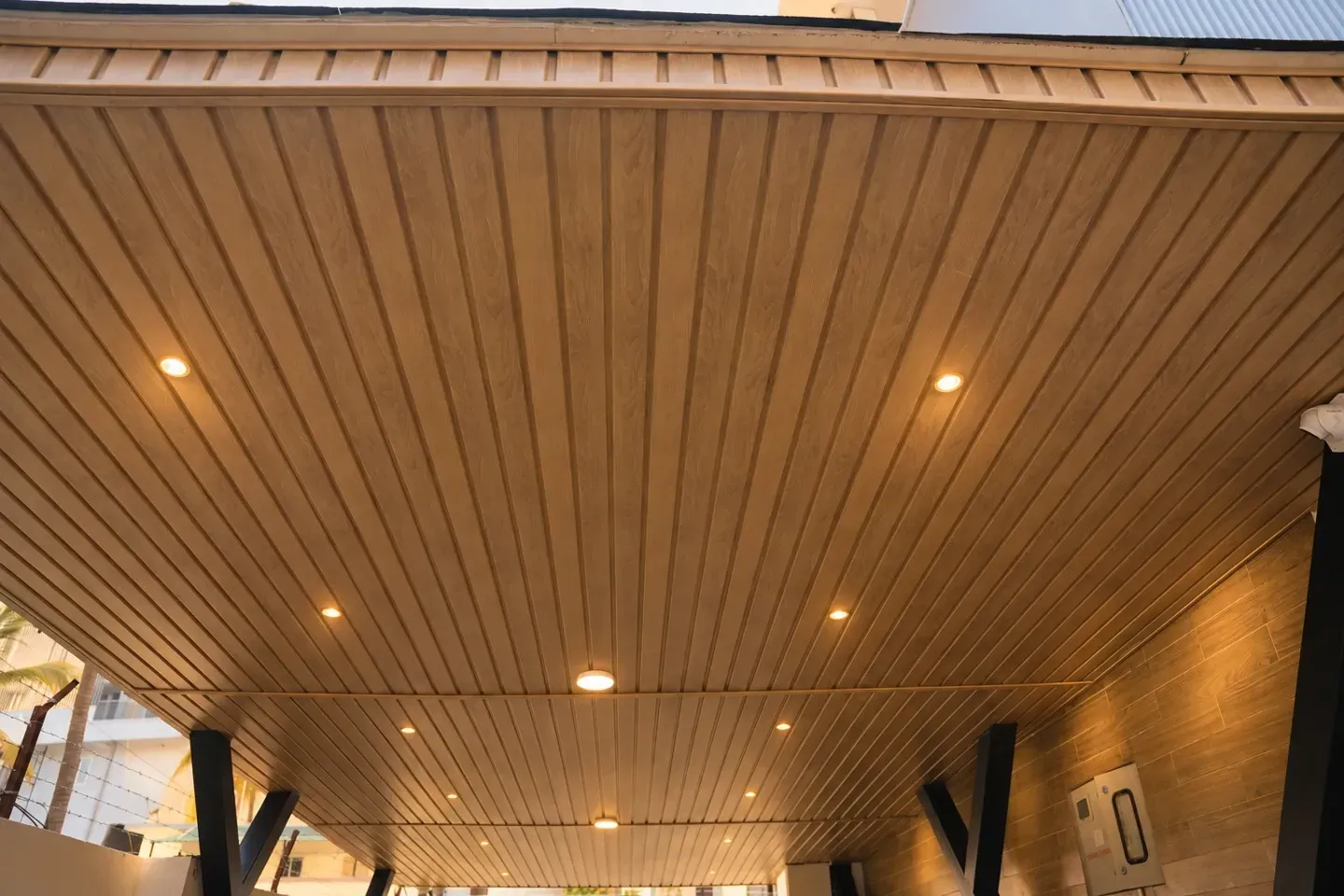 Enhanced upward view of the timber-toned pergola ceiling with recessed spotlights
