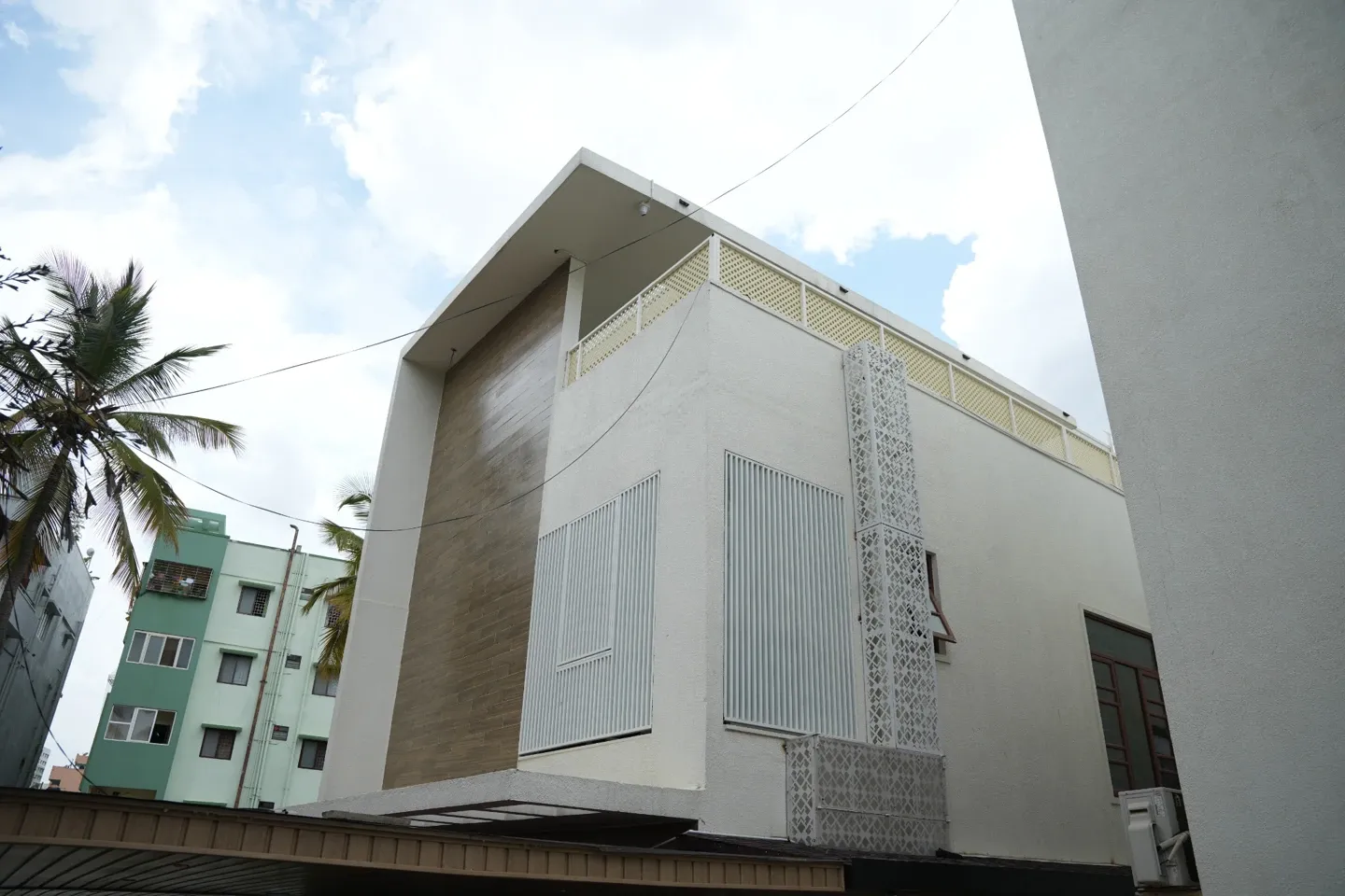 Daytime view of the villa exterior with tall white screens and patterned facade panels