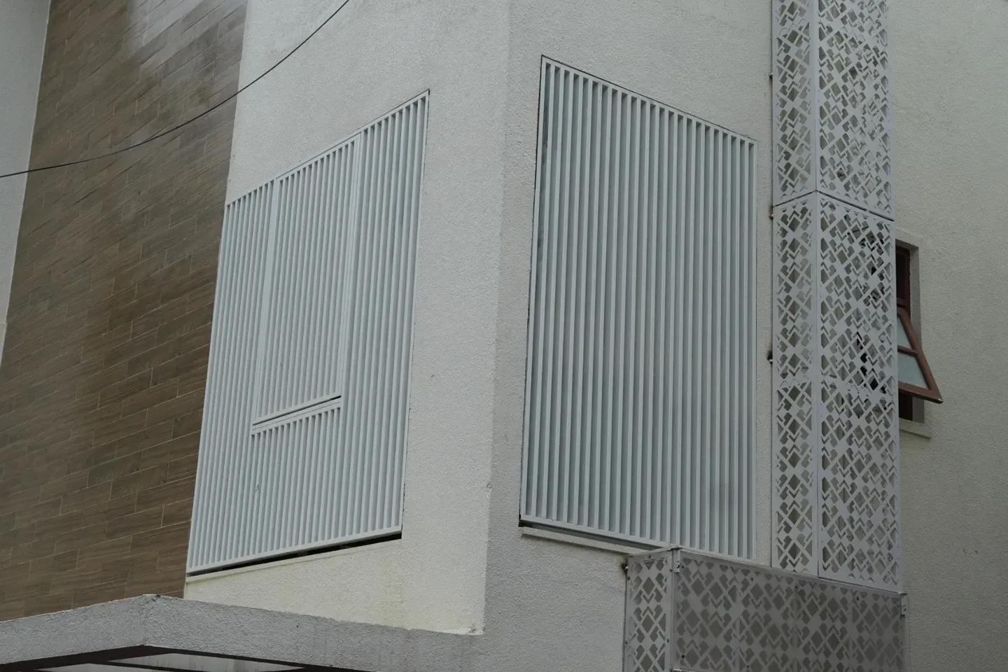 Close view of tall white metal screens and decorative patterned panels on the villa exterior
