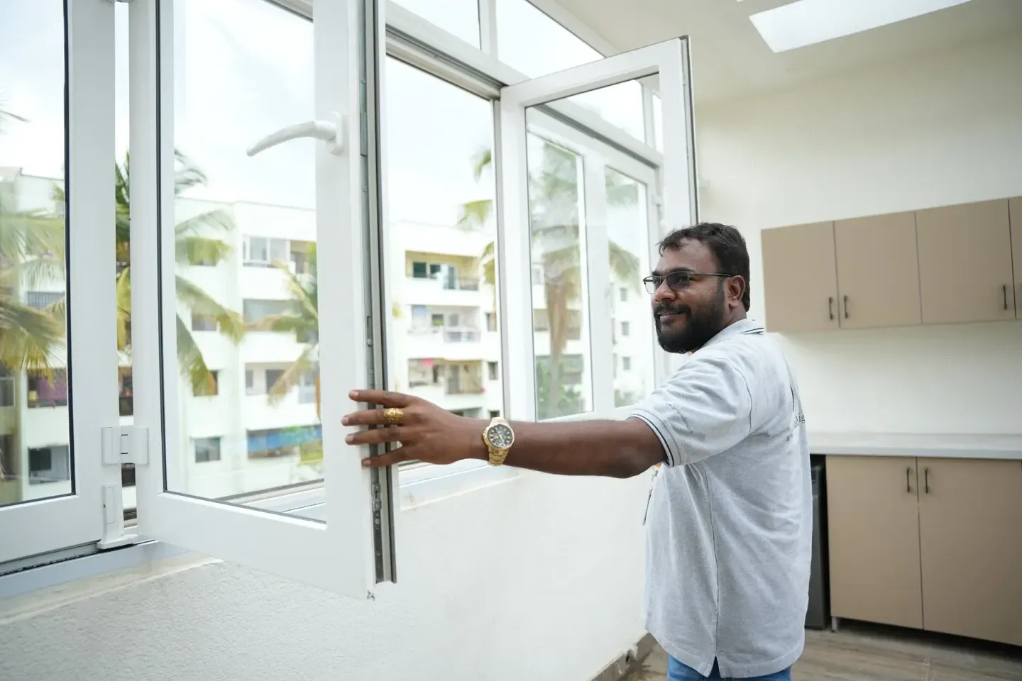 A man demonstrating an open white-framed window inside the villa