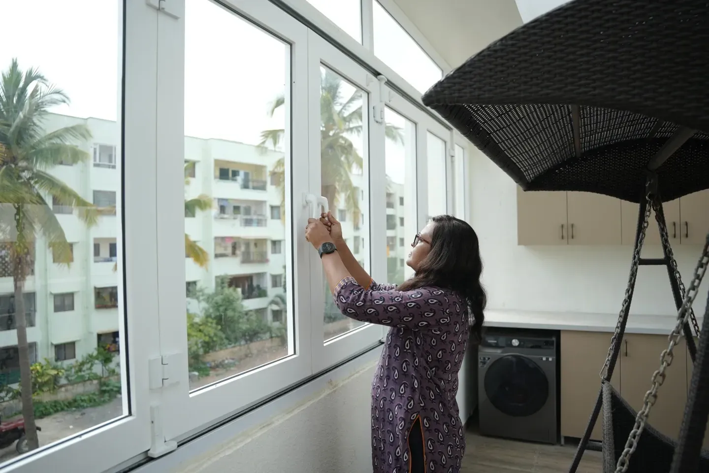 A woman looking at the handle of a white-framed window inside the villa