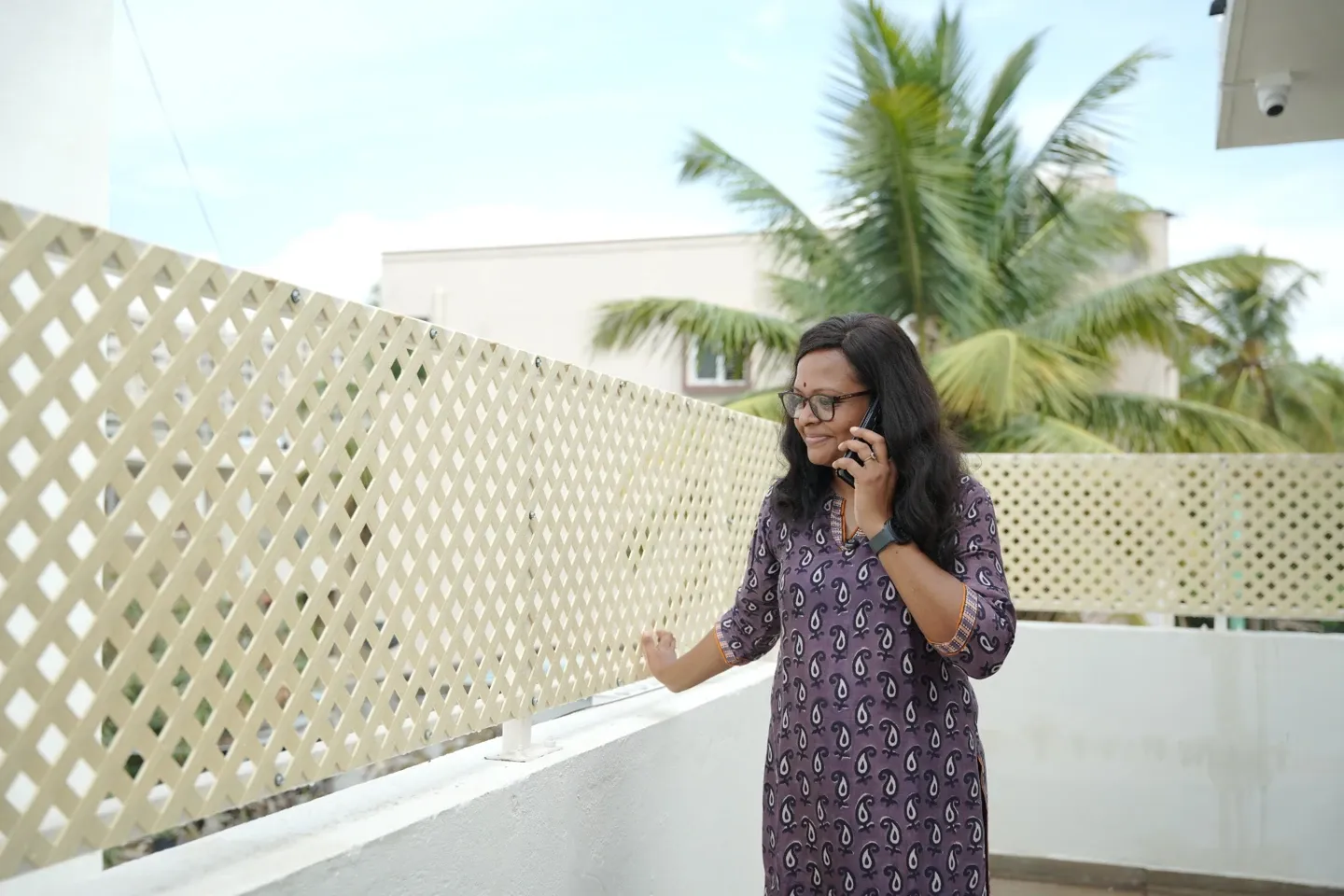 A woman beside white lattice privacy panels on an outdoor balcony