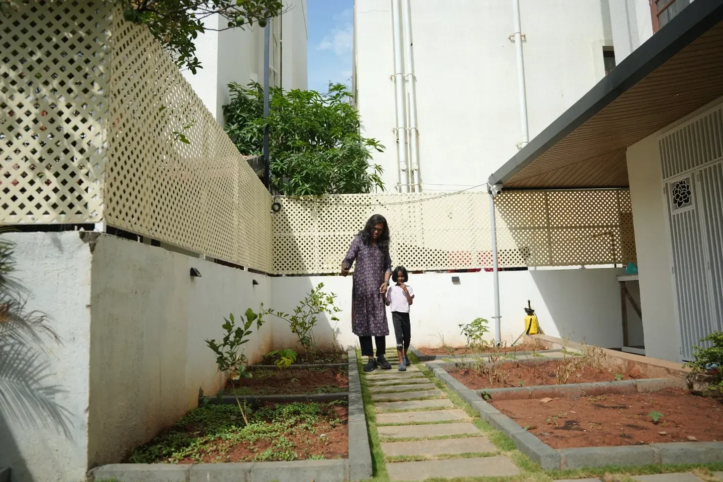 A woman in a garden passage with white lattice panels and a stepping-stone path