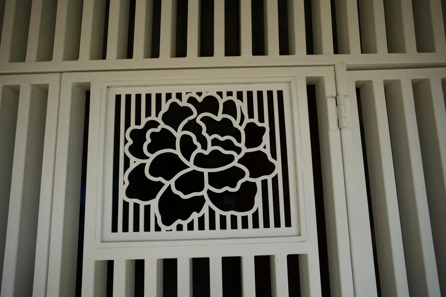 Close-up of a floral metal panel within a white entrance gate