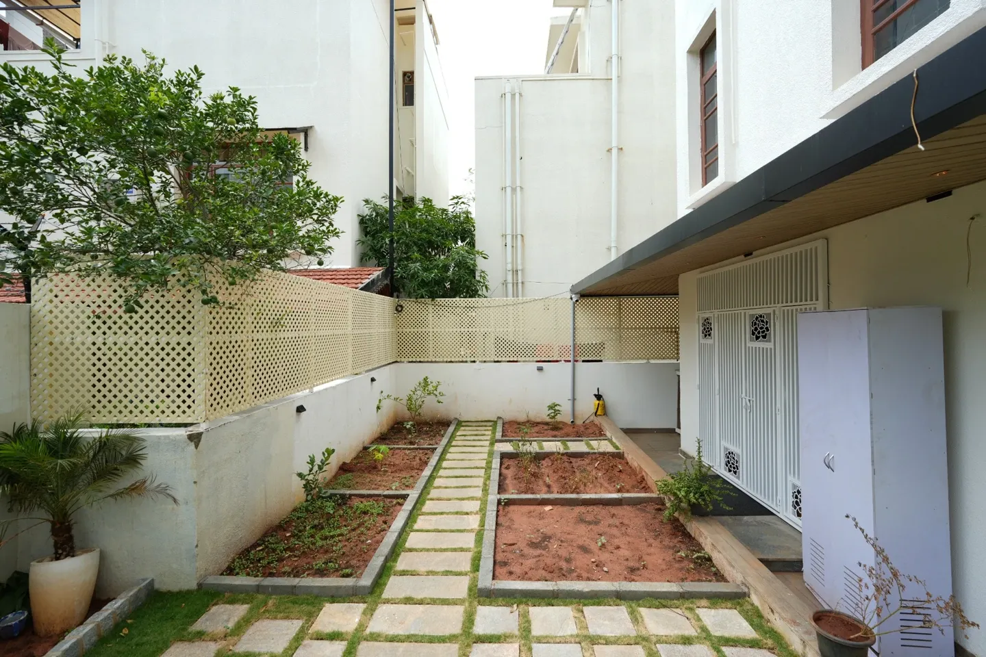 Garden passage beside the villa with a stepping-stone path, lattice screens and an entrance gate