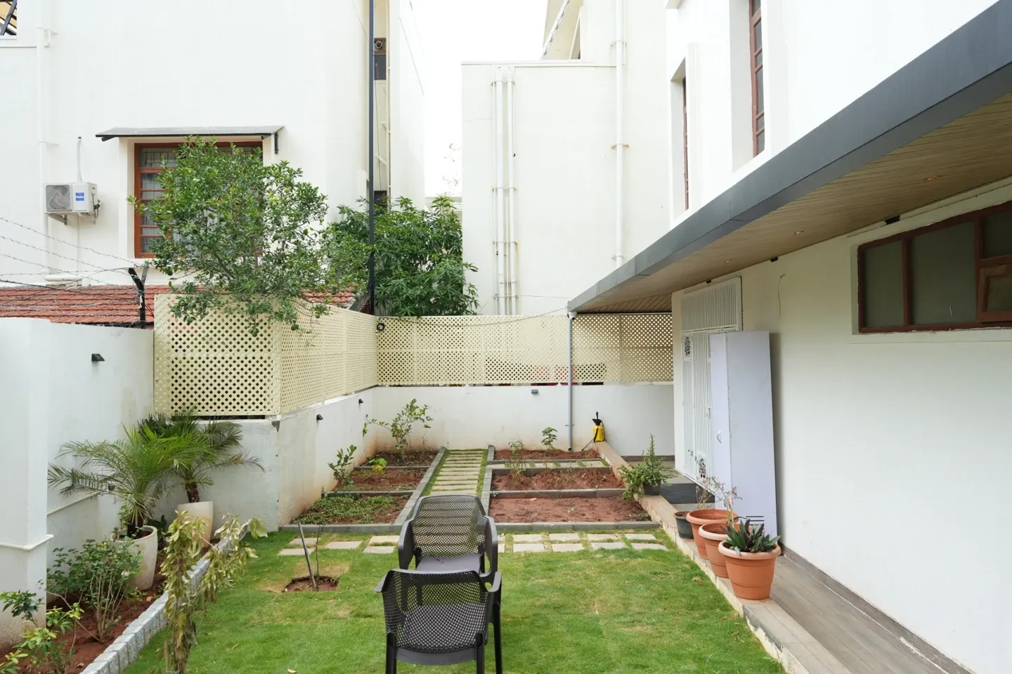 Wide garden view showing the lawn, stepping stones, lattice boundary and sheltered villa entrance