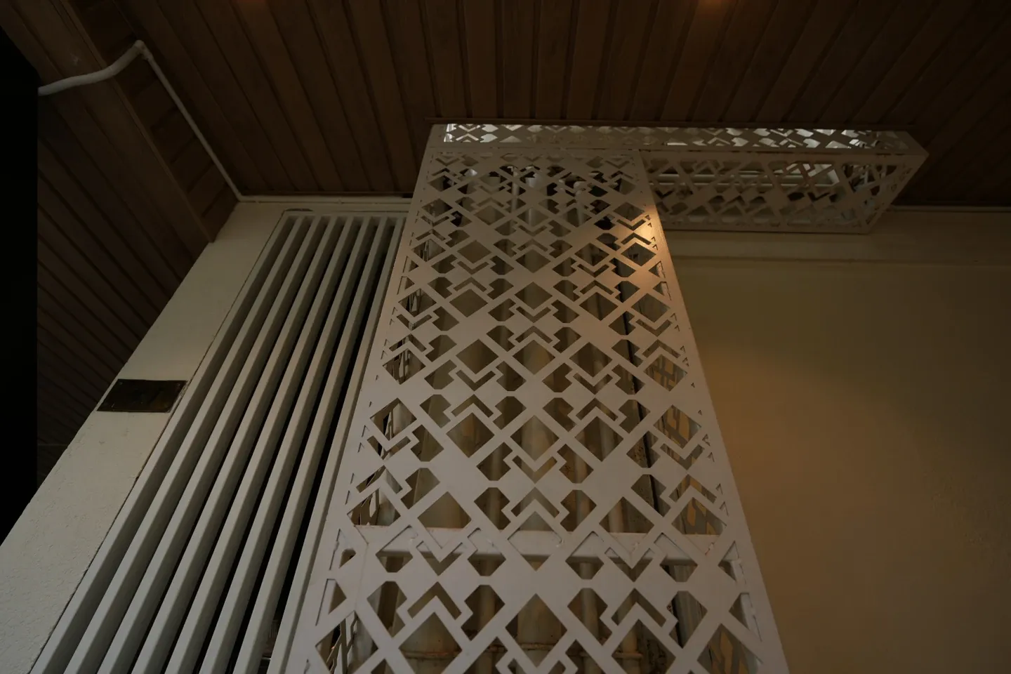 Close-up of a white decorative metal panel beneath a timber-toned canopy