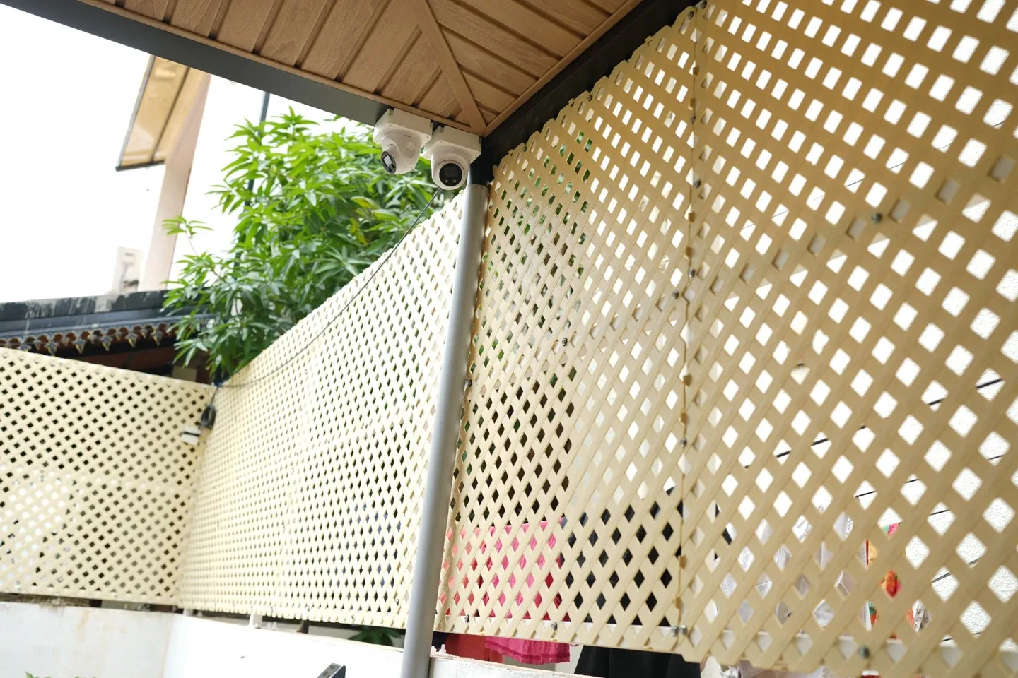 Pale lattice panels beneath the corner of the canopy with plants beyond