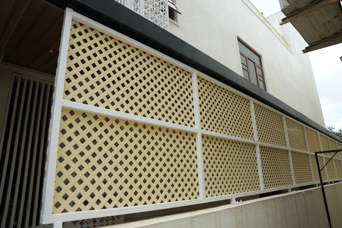 Exterior view of framed lattice panels running along the villa below a dark roof edge