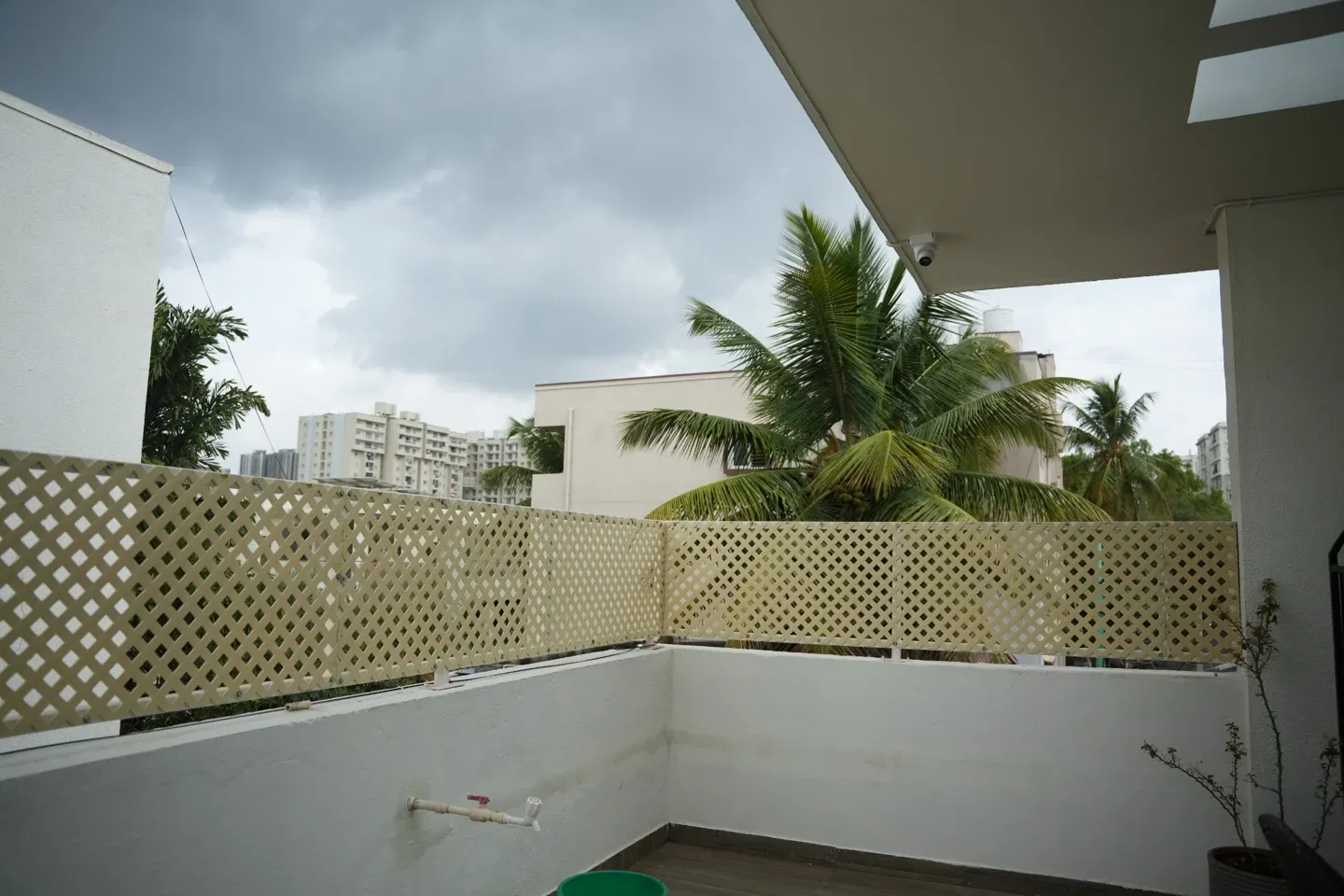 View of lattice panels along a white terrace parapet with palms beyond